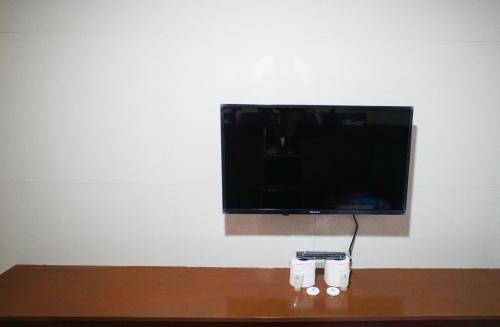 a flat screen tv on a wall with two glasses at ParmView Inn in Legazpi