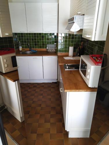 d'une cuisine avec des placards blancs et du carrelage marron au sol. dans l'établissement AGTBAB, à Biarritz