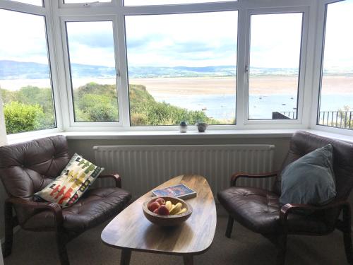 a living room with two chairs and a table and windows at Seaview Cottage in Aberdyfi