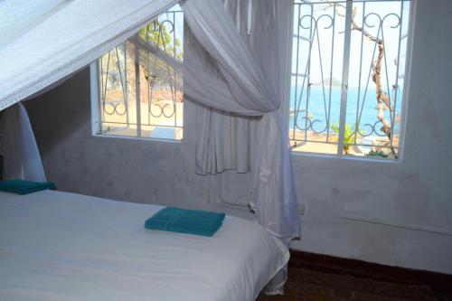 a bedroom with a bed and two windows with the ocean at Kuwona Cottage in Senga