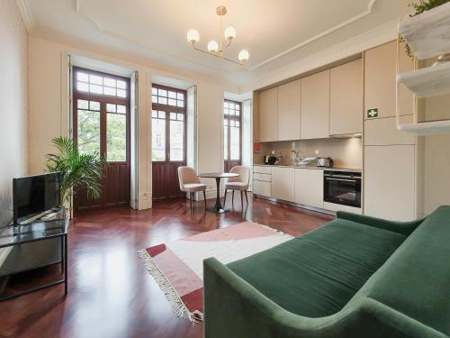 een woonkamer met een groene bank en een keuken bij Trindade Premium Apartments in Porto
