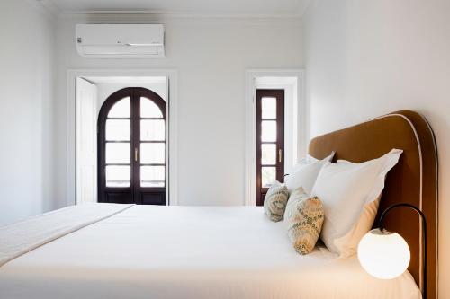 una camera da letto con un letto con lenzuola e cuscini bianchi di Trindade Premium Apartments a Porto