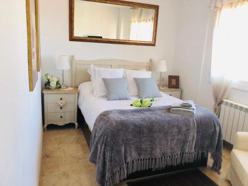 um quarto com uma cama com um cobertor e um espelho em Apartamento con terraza y piscina en Malgrat de Mar em Malgrat de Mar
