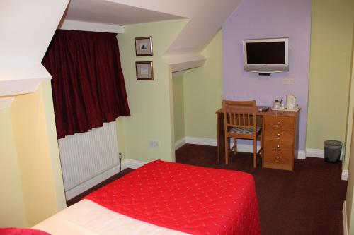 a bedroom with a bed and a desk with a television at The Abbey House Hotel in Reading