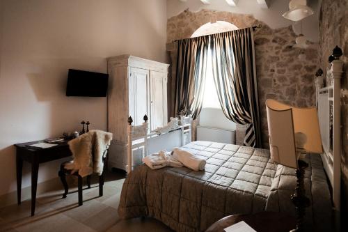 a bedroom with a bed and a desk in it at Dimora di Catullo - Ospitalità di Charme in Palazzolo Acreide