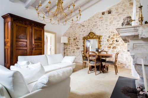 a living room with white furniture and a stone wall at Dimora di Catullo - Ospitalità di Charme in Palazzolo Acreide