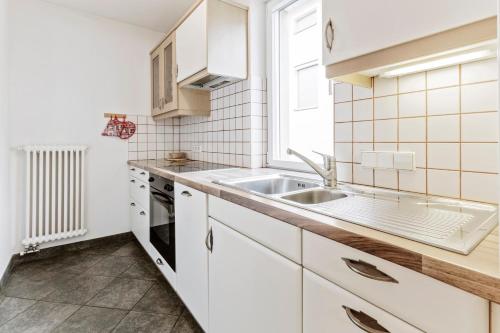 a kitchen with white cabinets and a sink at Apartments Petlin in Ortisei