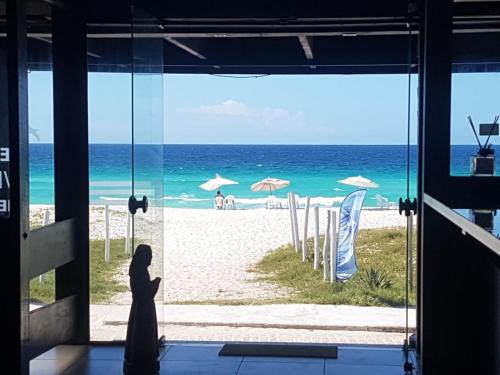 a woman standing in front of a window looking out at the beach at Pousada do Albatroz in Cabo Frio
