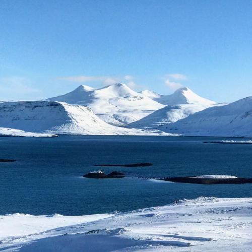 a large body of water with snow covered mountains at Hvammsvík Nature Resort in Kjósahreppur