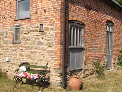 a bench sitting in front of a brick building at Manor Holding Byre in Bewdley