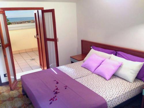- une chambre avec un lit doté de draps et d'oreillers violets dans l'établissement Residence Carina, à Bibione