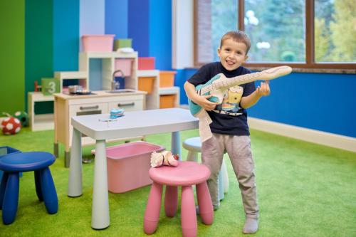 a young boy holding a toy baseball bat in a classroom at Evita Hotel & SPA in Tleń