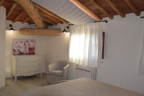 een slaapkamer met een bed, een stoel en een dressoir bij Le Bozze "Il Frantoio" con piscina, Wi-Fi, posto auto in Castagneto Carducci