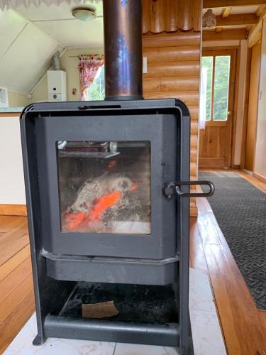a stove in a living room with a fire at Cabaña La Vasca in Puerto Tranquilo