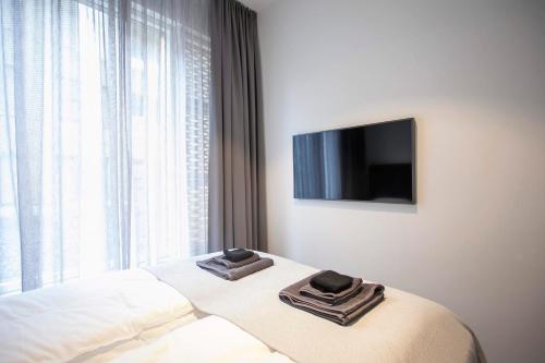 a bedroom with a bed with towels and a television at GreenKey Suite T21 in Reykjavík