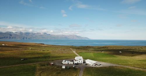 an aerial view of a house in a field with the ocean at Saltvík Farm Guesthouse in Húsavík