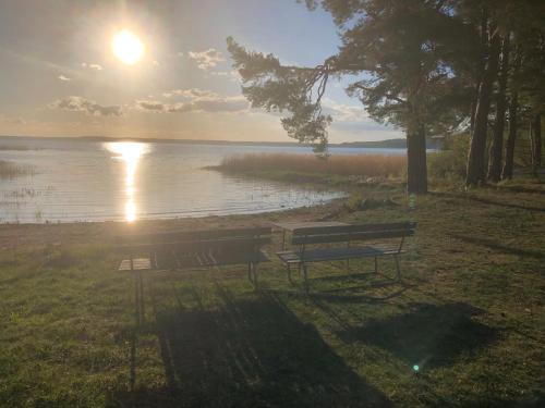 a park bench sitting next to a lake with the sunset at Villa Lillgården with Sauna and Jacuzzi in Norrköping