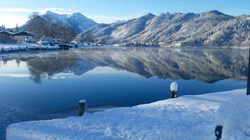 a body of water with snow on the ground and mountains at Apartment Seeglück am Schliersee - modern, zentral, perfekt für Familien in Schliersee