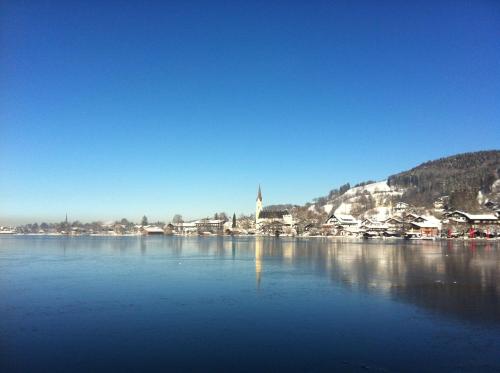 a large body of water with houses and a church at Apartment Seeglück am Schliersee - modern, zentral, perfekt für Familien in Schliersee