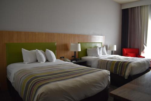 a hotel room with two beds and a red chair at Country Inn & Suites by Radisson, Hagerstown, MD in Hagerstown