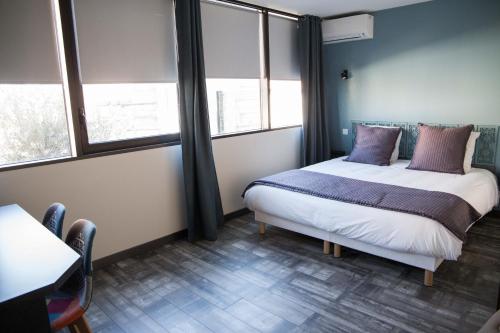 a bedroom with a bed with purple pillows and windows at Appart-hôtel Chanzy / Angoulême in Angoulême