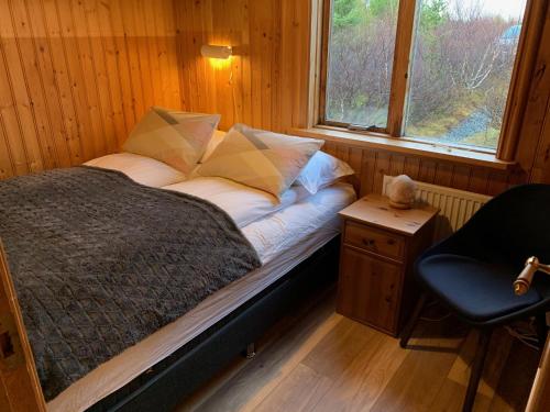 a bed in a room with a chair and a window at Holt in Jarðlangsstaðir