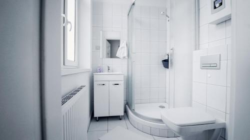 a white bathroom with a toilet and a sink at Rooms Śląska in Bydgoszcz