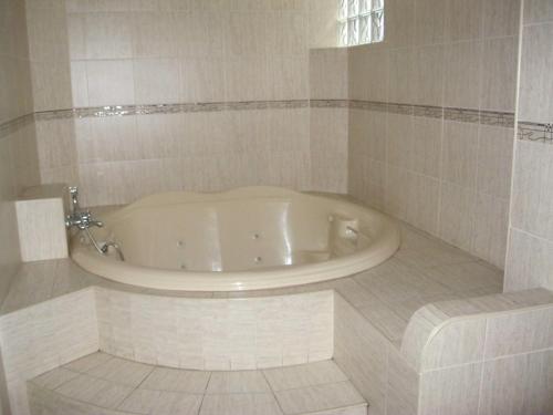 a bath tub in a bathroom with a tiled floor at Hostal Hostello - Lima Airport in Lima