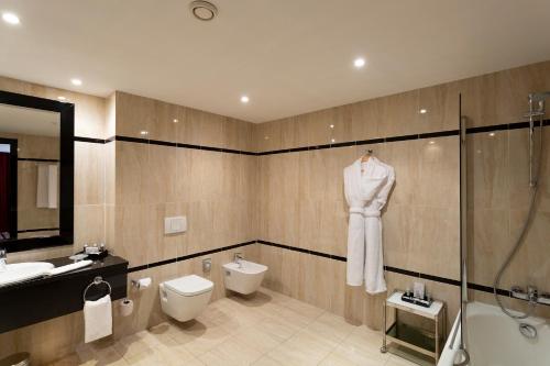 La salle de bains est pourvue d'un peignoir blanc accroché au mur. dans l'établissement Occidental Lac Tunis, à Tunis