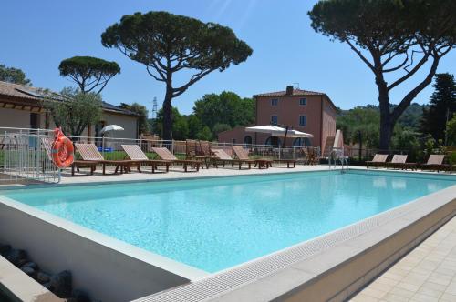 Una gran piscina con sillas y un edificio. en Le Bozze "Il Frantoio" con piscina, Wi-Fi, posto auto, en Castagneto Carducci