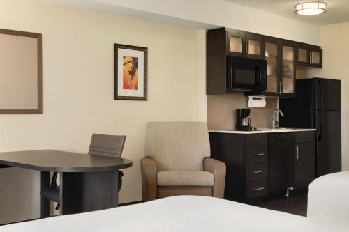 a hotel room with a kitchen and a table and a room at Park Inn by Radisson, Calgary Airport North, AB in Calgary