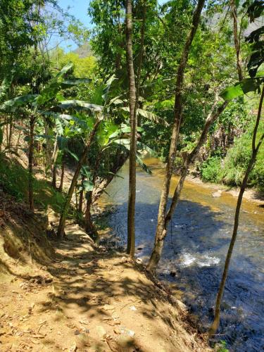 un chemin de terre à côté d'une rivière arborée dans l'établissement Nina-Flor Pousada Lumiar, à Lumiar