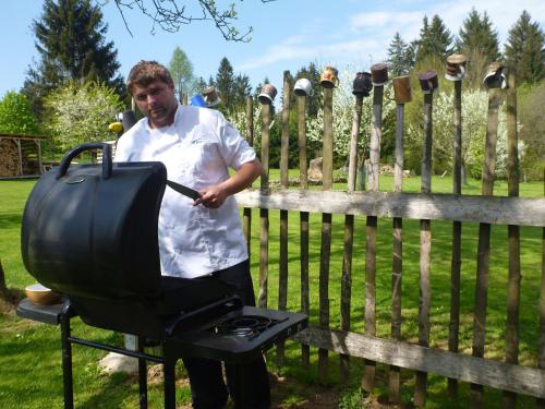 Um homem está a cozinhar numa churrasqueira. em Pension Klokočí em Sněžné