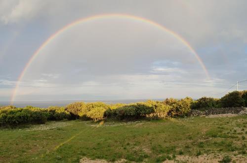 a rainbow in the sky over a field at Holiday home Verin in Mali Lošinj