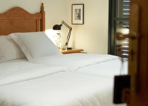 a bedroom with a white bed and a lamp at Hostal Can Maret in Vilademuls