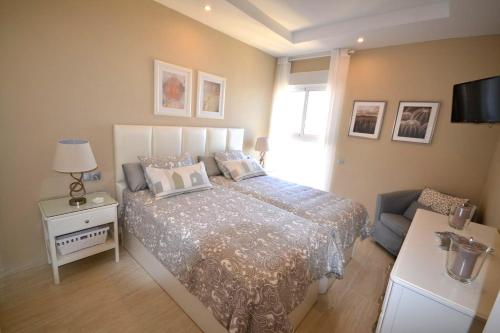 1 dormitorio con cama, sofá y TV en Fuengirola. Bonito apartamento en Paseo Marítimo. Espectaculares vistas al mar. Primera línea en Fuengirola