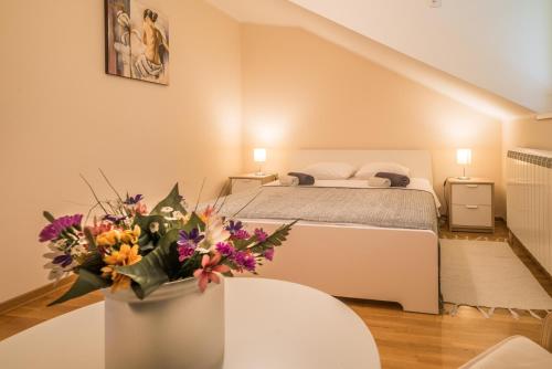 1 dormitorio con 1 cama y un jarrón de flores sobre una mesa en Skadarlija City Break, en Belgrado