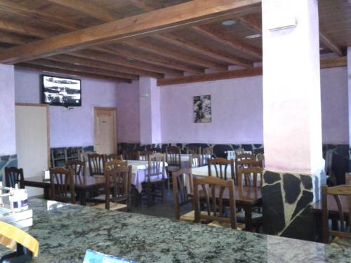 a dining room with tables and chairs and a tv at Hostal El Olmo in Camarena de la Sierra