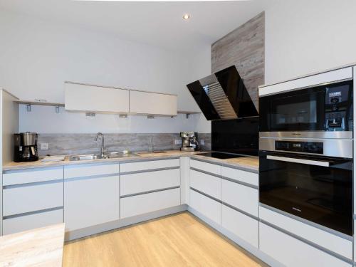 a kitchen with white cabinets and black appliances at Sielhof Ditzum, 45222 in Ditzum