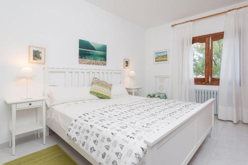 ein weißes Schlafzimmer mit einem weißen Bett und einem Fenster in der Unterkunft Villa Son Serra in Son Serra de Marina