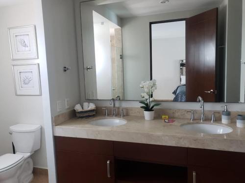 a bathroom with two sinks and a toilet and a mirror at Big Luxury Condo - Zona Dorada in Mazatlán