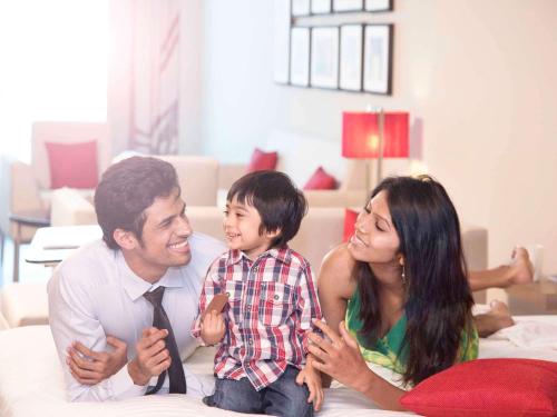 a man and a woman and a child sitting on a bed at Novotel Ahmedabad in Ahmedabad