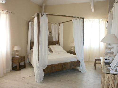 Chambres d'Hôtes Domaine de Beunes في Pailloles: غرفة نوم مع سرير مظلة مع ستائر بيضاء