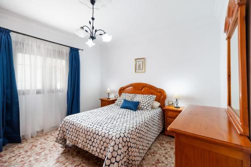 コニル・デ・ラ・フロンテーラにあるApartamento Virtudesのベッドルーム1室(ベッド1台、ドレッサー、青いカーテン付)