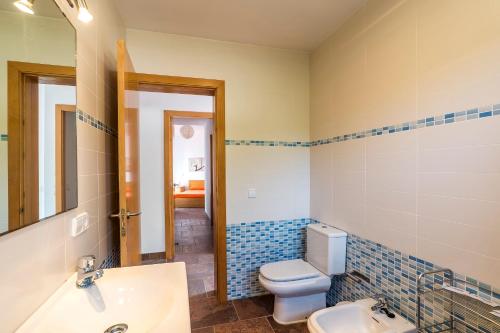 een badkamer met een toilet, een wastafel en een spiegel bij Villa Eduard in Binibeca