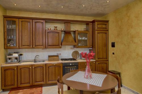 a kitchen with wooden cabinets and a table with a vase of flowers at Villa Nino in Petacciato
