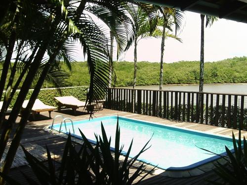 a swimming pool in a resort with palm trees at Pousada Canto do Rio in Prado