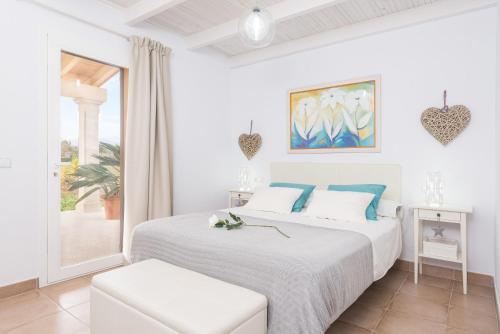 a white bedroom with a bed and a window at S'hortet in Alcudia