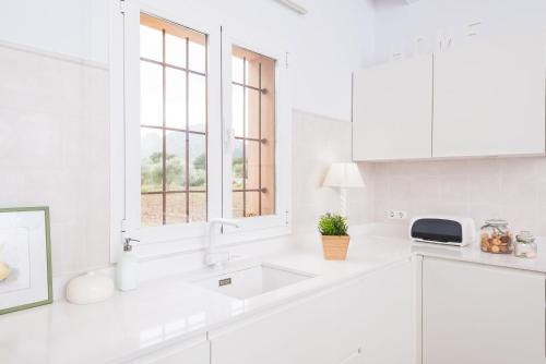 een witte keuken met een wastafel en een raam bij S'hortet in Alcudia