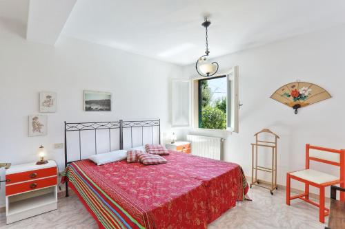 a bedroom with a bed and a chair and a window at Il giardino nel sole Bilo in Capoliveri